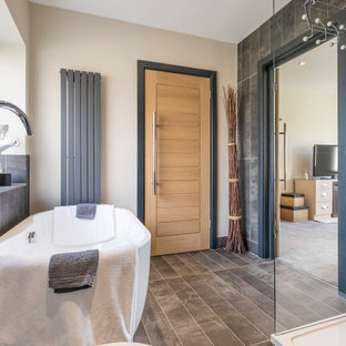 Inspiration for a large contemporary ensuite bathroom in Sussex with a freestanding bath, a corner shower, grey tiles, porcelain tiles, beige walls, grey floors and a hinged door.