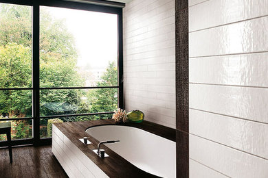 Example of a mid-sized trendy master ceramic tile dark wood floor bathroom design in Boston with an undermount tub and white walls