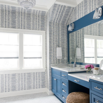 Beach style gray floor bathroom photo in New York with recessed-panel cabinets, blue cabinets, multicolored walls, an undermount sink and white countertops