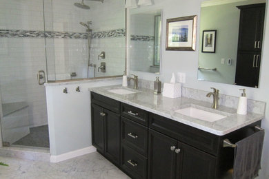 This is an example of a traditional ensuite bathroom in New York with marble worktops, stone tiles, marble flooring, recessed-panel cabinets, dark wood cabinets, an alcove shower, white tiles, blue walls and a submerged sink.