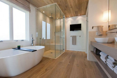 Modern inredning av ett mellanstort en-suite badrum, med öppna hyllor, beige skåp, ett fristående badkar, en hörndusch, beige kakel, porslinskakel, vita väggar, ljust trägolv, ett fristående handfat, bänkskiva i kvarts, beiget golv och dusch med gångjärnsdörr