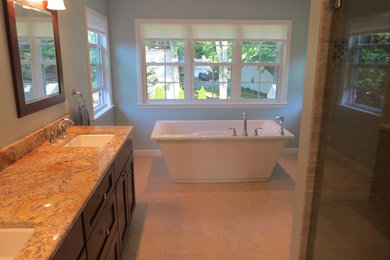 Exemple d'une salle de bain principale tendance en bois foncé de taille moyenne avec un placard à porte shaker, une baignoire indépendante, une douche d'angle, un mur bleu, un sol en travertin, un lavabo encastré et un plan de toilette en granite.