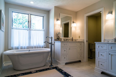 Example of a mid-sized transitional master gray tile freestanding bathtub design in Cleveland with shaker cabinets, white cabinets, a one-piece toilet, beige walls and marble countertops