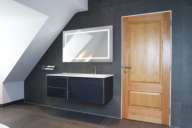 This is an example of a contemporary bathroom in Surrey with glass-front cabinets, blue cabinets, a freestanding bath, a corner shower, a wall mounted toilet, solid surface worktops and an open shower.