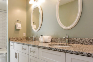 Example of a mid-sized transitional master brown tile and porcelain tile porcelain tile and brown floor bathroom design in Birmingham with shaker cabinets, white cabinets, green walls, an undermount sink, granite countertops and a hinged shower door