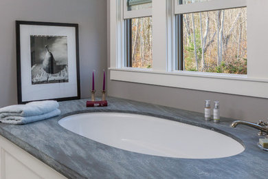 Inredning av ett klassiskt stort en-suite badrum, med luckor med profilerade fronter, vita skåp, ett undermonterat badkar, vit kakel, marmorkakel, grå väggar, marmorgolv, ett undermonterad handfat och marmorbänkskiva
