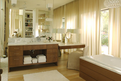 Example of a large transitional light wood floor drop-in bathtub design in Tampa with an undermount sink, flat-panel cabinets, medium tone wood cabinets, marble countertops and beige walls