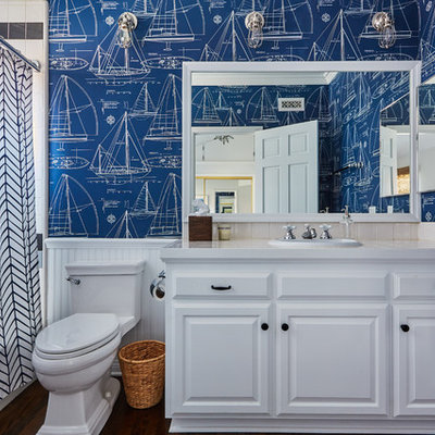 Mid-sized elegant kids' beige tile medium tone wood floor bathroom photo in Orange County with raised-panel cabinets, white cabinets, blue walls, a drop-in sink and tile countertops