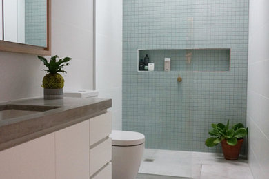 メルボルンにあるコンテンポラリースタイルのおしゃれなマスターバスルーム (白いキャビネット、白い壁、アンダーカウンター洗面器、コンクリートの洗面台、コーナー設置型シャワー、分離型トイレ、青いタイル、白いタイル、オープンシャワー) の写真