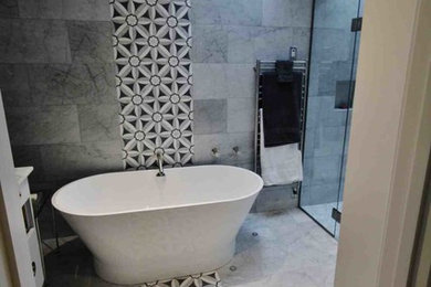 Modelo de cuarto de baño principal actual de tamaño medio con bañera exenta, ducha empotrada, baldosas y/o azulejos grises, paredes grises, suelo de mármol y suelo gris