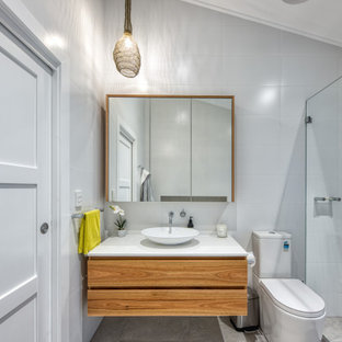 This is an example of a mid-sized beach style 3/4 bathroom in Sydney with flat-panel cabinets, medium wood cabinets, an alcove shower, a one-piece toilet, gray tile, porcelain tile, a vessel sink, grey floor, white benchtops, a single vanity and a freestanding vanity.