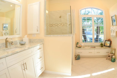 Example of a mid-sized beach style master gray tile, multicolored tile, white tile and porcelain tile ceramic tile corner shower design in Orange County with shaker cabinets, white cabinets, a one-piece toilet, yellow walls, an undermount sink and marble countertops
