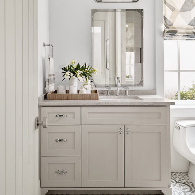 Inspiration for a small coastal 3/4 white tile ceramic tile, gray floor and double-sink bathroom remodel in Houston with recessed-panel cabinets, white cabinets, a one-piece toilet, white walls, a drop-in sink, a hinged shower door, gray countertops and a built-in vanity