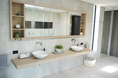 Imagen de cuarto de baño principal costero con puertas de armario de madera clara y encimera de madera