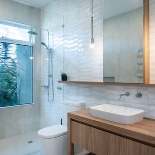 Design ideas for a large contemporary master bathroom in Melbourne with furniture-like cabinets, medium wood cabinets, an open shower, a one-piece toilet, white tile, ceramic tile, white walls, porcelain floors, a drop-in sink, laminate benchtops, beige floor, an open shower and brown benchtops.
