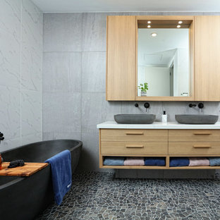 Mid-sized contemporary master bathroom in Melbourne with furniture-like cabinets, light wood cabinets, a freestanding tub, porcelain tile, a vessel sink, engineered quartz benchtops, multi-coloured floor, grey walls, mosaic tile floors and white benchtops.