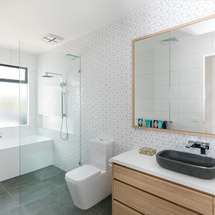 Large beach style master bathroom in Other with flat-panel cabinets, light wood cabinets, an alcove tub, a curbless shower, a one-piece toilet, white tile, white walls, a vessel sink, grey floor, an open shower, ceramic tile, porcelain floors, engineered quartz benchtops and white benchtops.