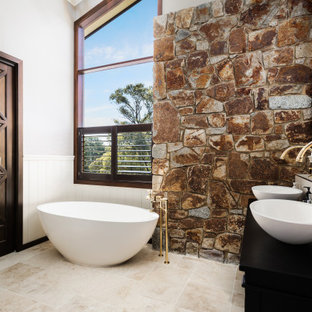 Design ideas for a mediterranean bathroom in Other with black cabinets, a freestanding tub, white tile, white walls, a vessel sink, beige floor, black benchtops, a double vanity, vaulted and decorative wall panelling.