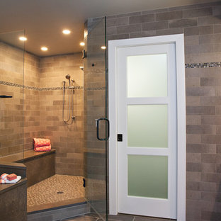 Modelo de cuarto de baño principal, bohemio, grande, con armarios con paneles lisos, puertas de armario de madera oscura, bañera encastrada sin remate, ducha abierta, baldosas y/o azulejos grises, baldosas y/o azulejos de piedra, paredes grises, suelo de baldosas de porcelana, lavabo sobreencimera y encimera de cuarcita
