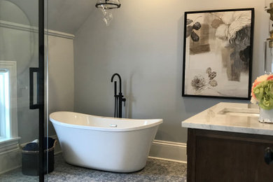 Bathroom - mid-sized transitional master ceramic tile, multicolored floor and single-sink bathroom idea in Ottawa with furniture-like cabinets, medium tone wood cabinets, a one-piece toilet, gray walls, an undermount sink, quartz countertops, gray countertops, a niche and a freestanding vanity