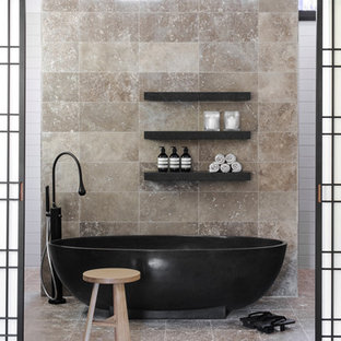 Foto di una stanza da bagno design con vasca freestanding, piastrelle beige, pavimento beige e piastrelle in travertino