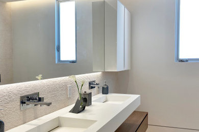 ロサンゼルスにあるラグジュアリーな中くらいなコンテンポラリースタイルのおしゃれなバスルーム (浴槽なし) (フラットパネル扉のキャビネット、茶色いキャビネット、置き型浴槽、コーナー設置型シャワー、壁掛け式トイレ、ベージュのタイル、石タイル、ベージュの壁、ライムストーンの床、一体型シンク、人工大理石カウンター、開き戸のシャワー、白い洗面カウンター、ニッチ、洗面台2つ、フローティング洗面台) の写真