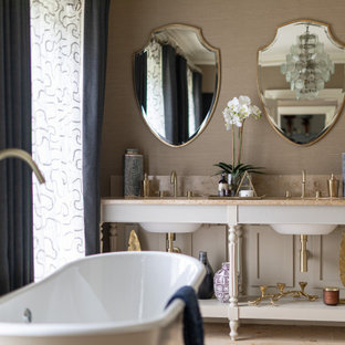 Inspiration for a medium sized classic ensuite bathroom in London with freestanding cabinets, white cabinets, a freestanding bath, beige walls, light hardwood flooring, a submerged sink, beige floors and beige worktops.