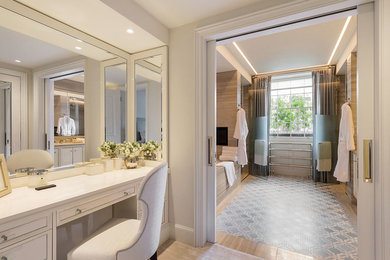 Photo of a large contemporary ensuite bathroom in London with flat-panel cabinets, white cabinets, a built-in bath, a walk-in shower, a wall mounted toilet, marble tiles, a built-in sink, marble worktops and a hinged door.