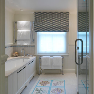 Example of a beach style multicolored tile and mosaic tile bathroom design in London with an undermount tub and beige walls