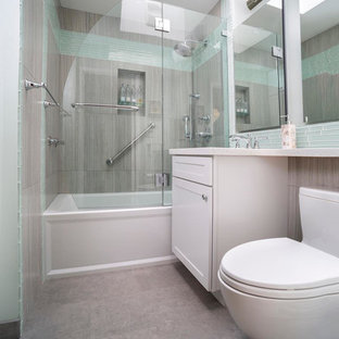 Foto di una piccola stanza da bagno con doccia minimal con ante con riquadro incassato, ante bianche, vasca ad alcova, vasca/doccia, WC a due pezzi, piastrelle di vetro, pareti grigie, pavimento con piastrelle in ceramica, piastrelle blu, lavabo sottopiano, top in quarzo composito, pavimento grigio e porta doccia a battente