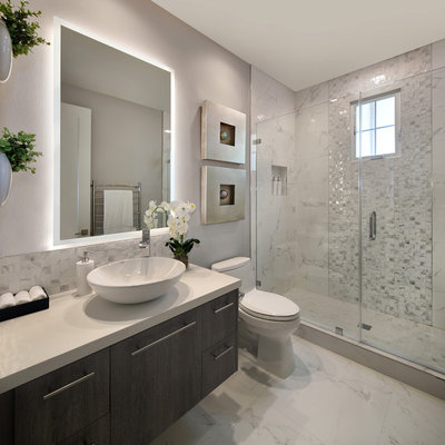 Alcove shower - small modern 3/4 white tile and porcelain tile porcelain tile and white floor alcove shower idea in Orange County with flat-panel cabinets, dark wood cabinets, a one-piece toilet, gray walls, a vessel sink, quartz countertops, a hinged shower door and white countertops