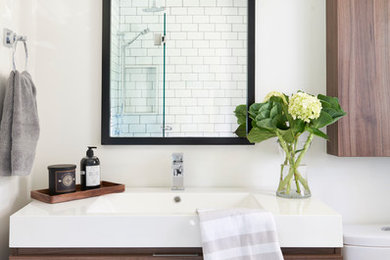 Inspiration for a small classic family bathroom in Toronto with flat-panel cabinets, medium wood cabinets, a built-in bath, a shower/bath combination, a two-piece toilet, multi-coloured tiles, mosaic tiles, grey walls, marble flooring, a trough sink and engineered stone worktops.