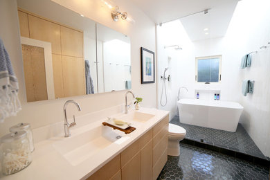 Example of a mid-sized trendy master white tile and porcelain tile porcelain tile bathroom design in San Francisco with flat-panel cabinets, light wood cabinets, a one-piece toilet, white walls, an integrated sink and solid surface countertops