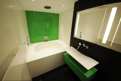 This is an example of a contemporary bathroom in Buckinghamshire with a built-in bath, a built-in shower, green tiles, solid surface worktops and white walls.