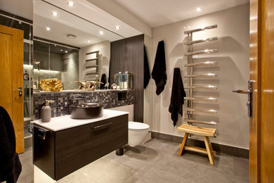 Medium sized contemporary sauna bathroom in Oxfordshire with flat-panel cabinets, dark wood cabinets, a double shower, a wall mounted toilet, brown tiles, porcelain tiles, beige walls, porcelain flooring, a vessel sink, engineered stone worktops, grey floors, a hinged door, white worktops, a single sink and a floating vanity unit.