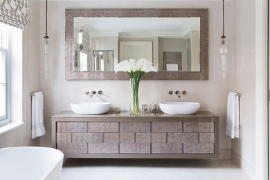 Modernes Badezimmer mit beigen Schränken, freistehender Badewanne, beiger Wandfarbe, Aufsatzwaschbecken, weißem Boden und beiger Waschtischplatte