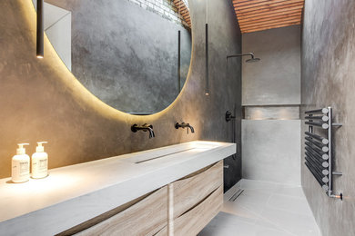 Diseño de cuarto de baño actual con puertas de armario de madera clara, ducha a ras de suelo, paredes verdes, lavabo de seno grande, suelo gris, ducha abierta, encimeras blancas y armarios con paneles lisos