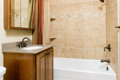 ワシントンD.C.にある小さなトラディショナルスタイルのおしゃれなバスルーム (浴槽なし) (レイズドパネル扉のキャビネット、濃色木目調キャビネット、アルコーブ型浴槽、シャワー付き浴槽	、ベージュのタイル、セラミックタイル、ベージュの壁、セラミックタイルの床、アンダーカウンター洗面器、御影石の洗面台、ベージュの床、シャワーカーテン) の写真