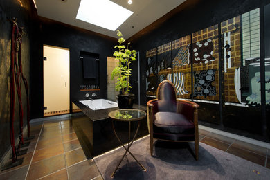 ロサンゼルスにあるアジアンスタイルのおしゃれな浴室 (ドロップイン型浴槽、アルコーブ型シャワー、黒い壁、スレートの床) の写真