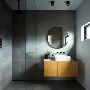 Inspiration for a modern 3/4 wet room bathroom in Sydney with flat-panel cabinets, medium wood cabinets, gray tile, grey walls, a vessel sink, wood benchtops, grey floor and brown benchtops.