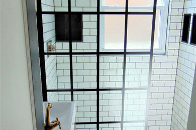 Small minimalist white tile and subway tile ceramic tile and black floor doorless shower photo in Cincinnati with medium tone wood cabinets, black walls and a wall-mount sink