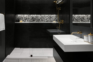 Modelo de cuarto de baño moderno con puertas de armario negras, paredes negras, aseo y ducha, lavabo suspendido, suelo gris y ducha abierta