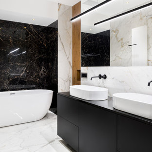 Inspiration for a mid-sized contemporary bathroom in Tampa with flat-panel cabinets, black cabinets, a freestanding tub, black and white tile, marble, white walls, marble floors, a vessel sink, white floor, a niche, a double vanity, a built-in vanity and wood walls.