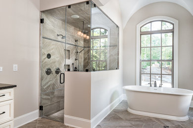 Example of a large minimalist master bathroom design in Raleigh with raised-panel cabinets, beige cabinets, a two-piece toilet, beige walls, an undermount sink, granite countertops and black countertops