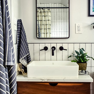 Foto de cuarto de baño principal, urbano, pequeño, con armarios con paneles lisos, puertas de armario de madera oscura, bañera empotrada, combinación de ducha y bañera, sanitario de una pieza, baldosas y/o azulejos blancos, baldosas y/o azulejos de cerámica, paredes blancas, suelo de azulejos de cemento, lavabo sobreencimera, encimera de cuarcita, suelo negro, ducha con cortina y encimeras blancas