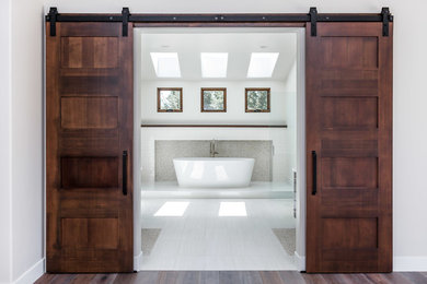 Imagen de cuarto de baño principal tradicional renovado grande con bañera exenta, baldosas y/o azulejos beige, suelo de baldosas tipo guijarro, paredes blancas y suelo de baldosas de porcelana