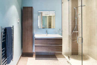 バンクーバーにある高級な中くらいなコンテンポラリースタイルのおしゃれなマスターバスルーム (家具調キャビネット、バリアフリー、青い壁、スレートの床、一体型シンク) の写真