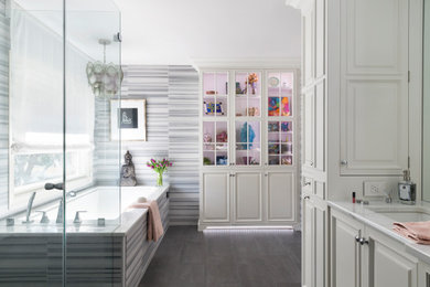 Idée de décoration pour une salle de bain tradition avec un placard avec porte à panneau surélevé, des portes de placard blanches, une baignoire encastrée, un carrelage gris, un lavabo encastré, un sol gris et un plan de toilette blanc.