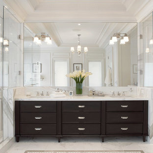 Example of a transitional master corner shower design in New York with recessed-panel cabinets, dark wood cabinets, a one-piece toilet, white walls and an undermount sink