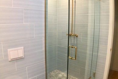ニューヨークにあるお手頃価格の中くらいなトランジショナルスタイルのおしゃれなバスルーム (浴槽なし) (アルコーブ型シャワー、壁掛け式トイレ、青いタイル、セラミックタイル、青い壁、磁器タイルの床、壁付け型シンク) の写真